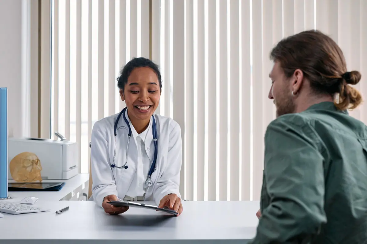 A doctor smiling while talking with a patient at her desk