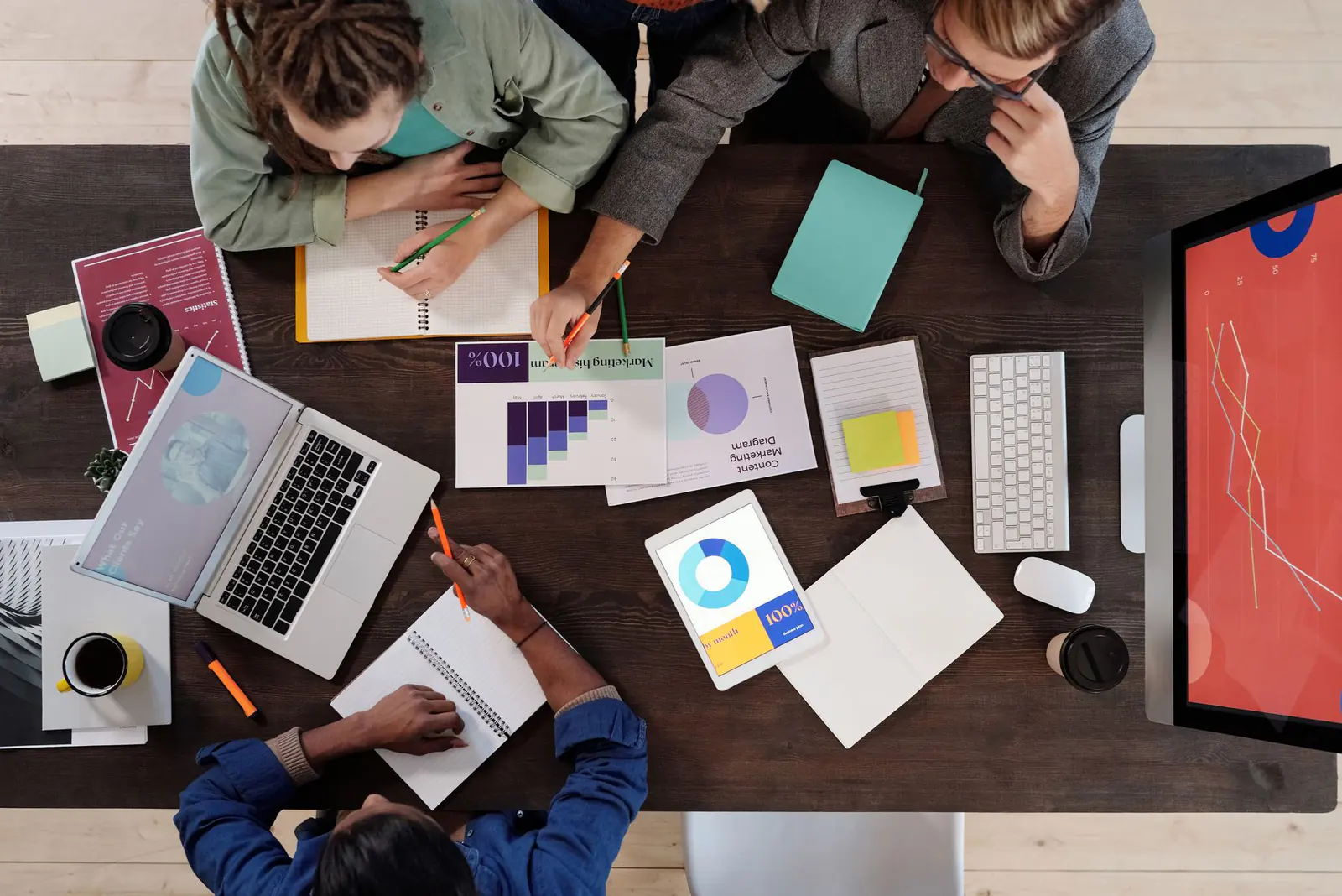 A small team planning around a desk of printed charts, seen from above