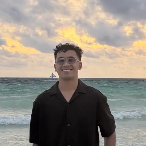 Raff Andrie C. Villaruz smiling, in a dark shirt by the sea