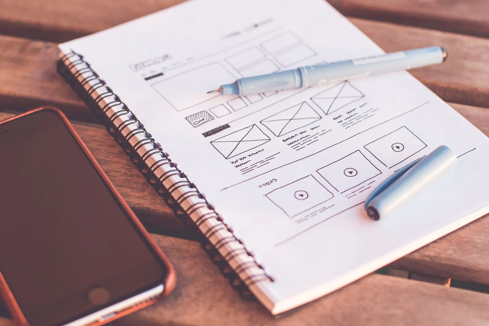 A website wireframe sketched in a notebook beside a phone